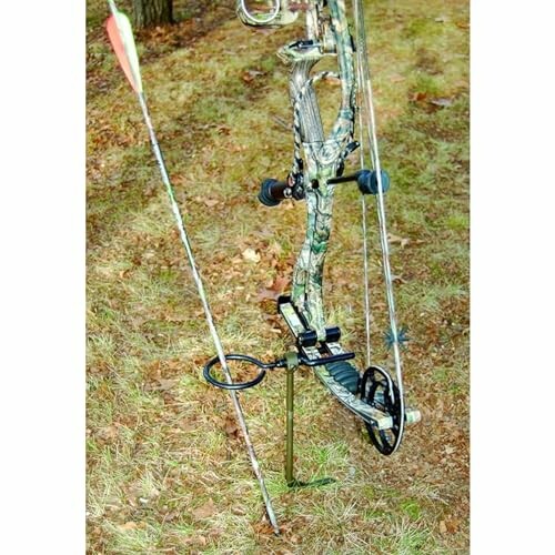 Compound bow with arrow resting on grassy ground.