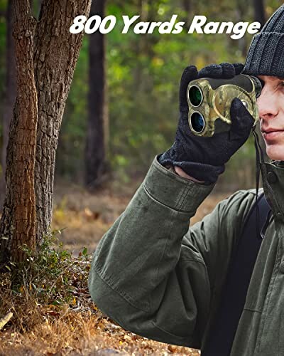 Man in outdoor clothing using a rangefinder in the woods